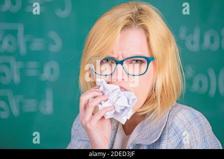 Professeur prêt à manger ses papiers. L'enseignant mange un morceau de papier absorbe l'information. Soif de connaissances. Une femme enseignant mange un morceau de papier froissé sur fond de tableau noir. Soif de connaissances. Banque D'Images