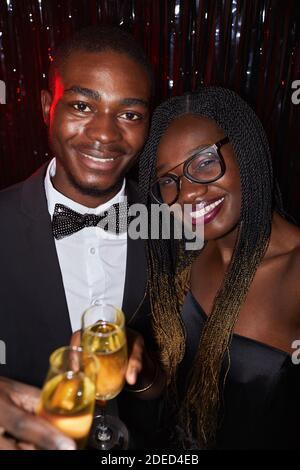 Portrait vertical de l'élégant couple afro-américain regardant l'appareil photo pendant faire la fête à la discothèque Banque D'Images