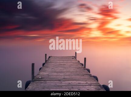 Coucher de soleil méditerranéen rouge et relaxant, sur le lac d'Albufera à Valence, en Espagne, sur une jetée en face de l'eau soyeuse Banque D'Images