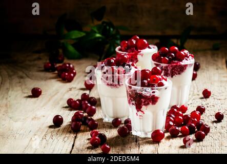 Dessert sucré de glace à la vanille avec sauce aux canneberges et baies canneberges fraîches, servi dans de petits verres sur le fond de bois ancien, sélectif Banque D'Images