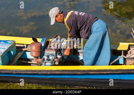 Homme local travaillant sur le moteur à longboat à Inle Lake, Myanmar (Birmanie), Asie en février Banque D'Images