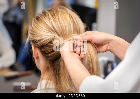 Gros plan des mains du coiffeur en braquant les cheveux du client dans un salon de beauté Banque D'Images