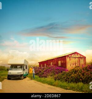 Heureux couple debout devant une voiture de camping, sur la route du Portugal Banque D'Images