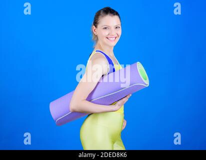 Entrer dans la gorge de yoga. Concept de cours de yoga. Le yoga comme loisir et sport. Pratiquer le yoga tous les jours. Fille souriante coupe slim athlète tenir le tapis de fitness. Fitness et étirements. Étirement des muscles. Banque D'Images