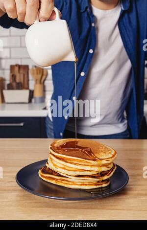 Homme versant avec du sirop d'érable sur la pile de crêpes Banque D'Images