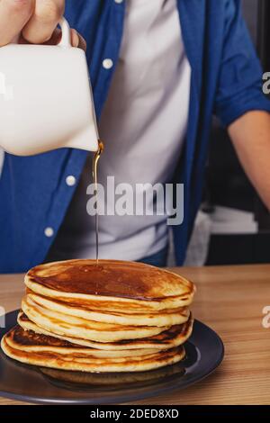 Homme versant avec du sirop d'érable sur la pile de crêpes Banque D'Images