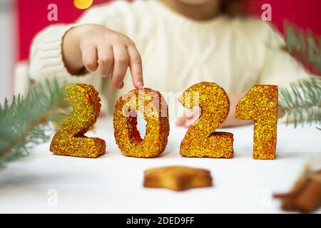 La main des enfants touche des chiffres dorés brillants 2021. Joyeux Noël et Bonne Année. Banque D'Images