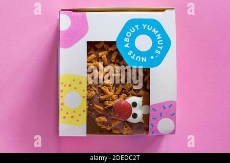 Rudolph le Donut à nez rouge dans une boîte fraîche de la boulangerie Chez Marks & Spencer, isolé sur fond rose - renne Donut pour Noël Banque D'Images