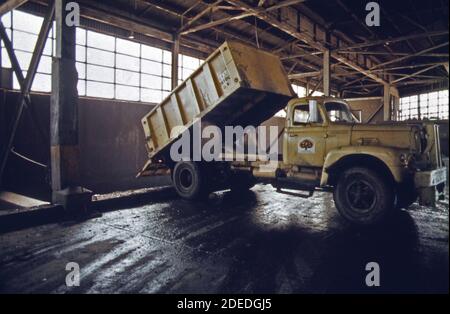 Photo des années 1970 - (1973) - camion à la 91e rue la station de transfert maritime vide les ordures dans la barge pour un voyage vers le bas La rivière East jusqu'au site d'enfouissement de Staten Island Banque D'Images