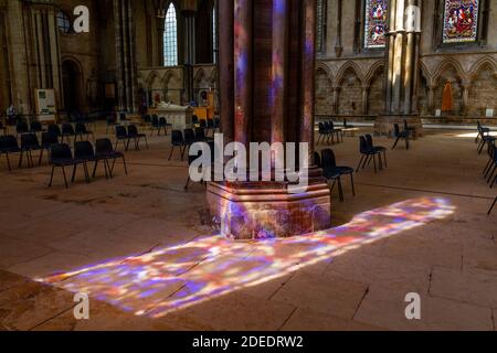 Fenêtre en vitraux illuminée sur le sol en pierre et la colonne à l'intérieur de la cathédrale Lincoln, Lincoln, Lincolnshire, Royaume-Uni. Banque D'Images