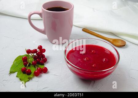 Composition d'automne avec confiture de viburnum, branches et feuilles de viburnum, serviette en lin blanc, tasse rose et cuillère en bois Banque D'Images