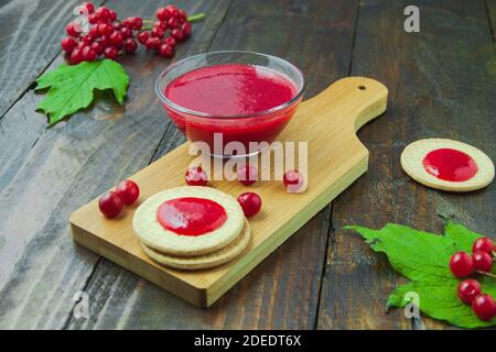 Confiture de Viburnum avec biscuits sur panneau de bois décoré de branches, feuilles. Composition d'automne. Concept de petit déjeuner Banque D'Images