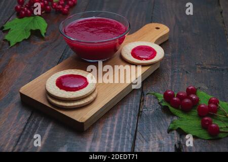 Confiture de Viburnum avec biscuits sur panneau de bois décoré de branches, feuilles. Composition d'automne. Concept de petit déjeuner Banque D'Images