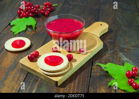 Confiture de Viburnum avec biscuits sur panneau de bois décoré de branches, feuilles. Composition d'automne. Concept de petit déjeuner Banque D'Images