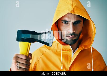 Portrait d'homme beau brutal en imperméable brillant tenant une grosse hache. Bûcheron, pêcheur à la hache Banque D'Images