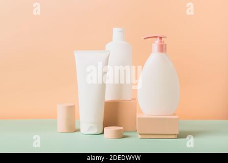 Groupe de cosmétiques en différents tubes et bouteilles sur un podium abstrait moderne sur fond pastel. Modèle pour la publicité de produits cosmétiques. Avant Banque D'Images