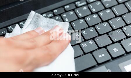 Désinfection manuelle, désinfection d'un clavier d'ordinateur portable moderne à l'aide d'un chiffon humide. Nettoyage des touches de l'ordinateur portable avec un chiffon humide, gros plan. Hygiène de l'espace de travail de bureau Banque D'Images