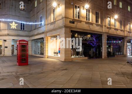 Magasin Topman & Topshop dans le centre commercial Southgate à côté d'une boîte téléphonique rouge britannique au crépuscule, Bath, Angleterre, Royaume-Uni Banque D'Images