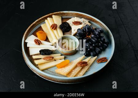 assiette de fromages avec une variété de fromages sur un noir arrière-plan Banque D'Images