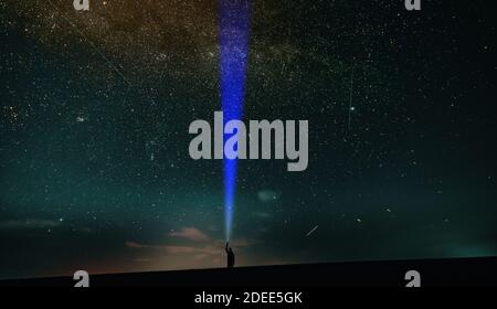 Homme avec une lampe de poche sur le fond du ciel nocturne. Banque D'Images