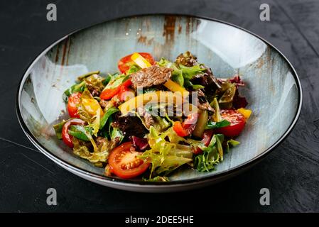 salade chaude avec steak de bœuf marbré sur fond noir Banque D'Images