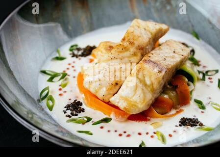 filet de morue grillé avec légumes et sauce sur un noir arrière-plan Banque D'Images
