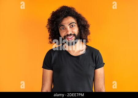 un homme arabe indien agréable en chemise regardant l'appareil photo, a un regard amical, un gars ouvert d'esprit isolé sur fond orange Banque D'Images