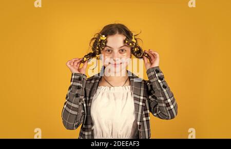 Conseils pour la coiffure des enfants. Outils de coiffure et accessoires de coiffure. Enfant avec des patches sur le visage. Posez avec des pillards. Bonne fille dans des pillards jouant au salon de coiffure. Bonne pour les cheveux Banque D'Images