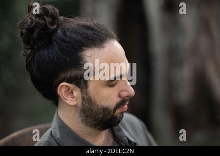 Une vue latérale d'un jeune homme barbu hispanique posant à l'appareil photo Banque D'Images