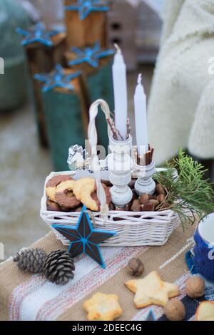 Panier en osier blanc, avec biscuits et noix et une branche d'épicéa, avec bougies blanches Banque D'Images