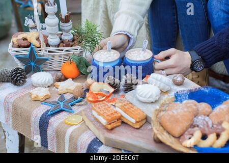 Décoration d'hiver, table douce. Mugs au cacao. Les mains des gens Banque D'Images