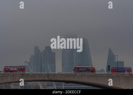 Londres, Royaume-Uni. 30 novembre 2020. La ville de Londres, partiellement cachée, offre une toile de fond grise aux autobus qui passent au-dessus du pont de Waterloo, dont beaucoup ont des messages qui s'affichent à Covid 19. Un matin brumeux, une certaine vie se poursuit à Londres alors que le second coronavirus Lockdown approche de sa fin crédit: Guy Bell/Alamy Live News Banque D'Images