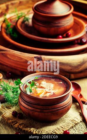 Soupe russe traditionnelle de choucroute, viande et pommes de terre dans un pot d'argile, fond de bois vintage, style rustique, concentration sélective Banque D'Images