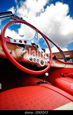 Low angle view de l'intérieur de belle voiture convertible classique. Sièges en cuir rouge et le volant en premier plan. Ciel clair en arrière-plan. Banque D'Images