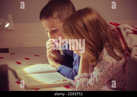 Deux heureux enfants d'enfant de la lecture réserve en lits superposés sous couverture Banque D'Images