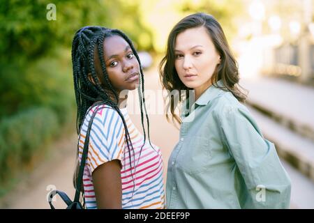 Deux jeunes amis regardant ensemble l'appareil photo dans la rue. Femmes multiethniques. Banque D'Images