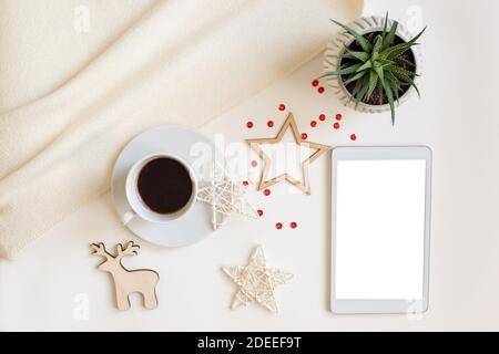 Une tablette numérique avec un écran vierge, se trouve sur une table blanche entourée de décorations de Noël en bois plates Banque D'Images