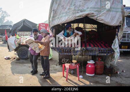 Alipur, Inde. 30 novembre 2020. Les agriculteurs sont vus lire des journaux, près d'un barrage routier de la police pendant qu'ils prennent part à la manifestation. Selon le syndicat des agriculteurs, des milliers d'agriculteurs de différents États se sont déplacés vers la capitale de l'Inde pour protester contre les nouvelles lois agricoles qui, selon eux, nuirait gravement à leurs revenus. Crédit : SOPA Images Limited/Alamy Live News Banque D'Images