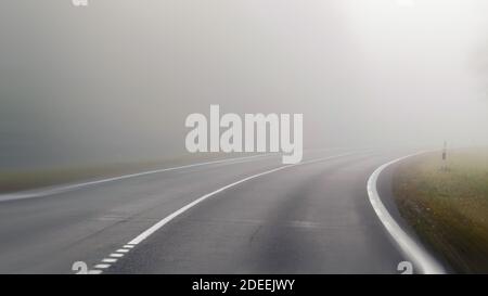 La conduite sur route de campagne dans le brouillard. Illustration des dangers de la conduite dans de mauvaises conditions météorologiques : brumeux, difficile de voir de l'avant Banque D'Images