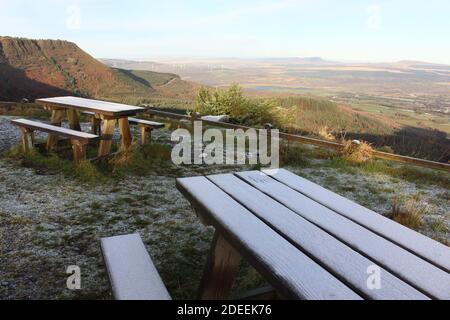 Une photographie d'un banc de pique-nique en bois givré au sommet d'un Point de vue sur la montagne dans le sud du pays de Galles surplombant le Brecons Beacons National stationnement Banque D'Images