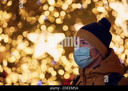 Jeune homme avec masque de visage contre arbre de Noël à Prague. Thèmes pandémie de coronavirus pendant les vacances de Noël et responsabilité personnelle. Banque D'Images