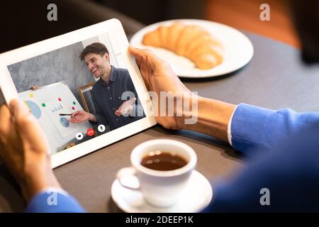 Homme d'affaires effectuant un appel vidéo sur une tablette ayant une réunion au café Banque D'Images