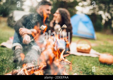 Beau couple torréfaction marshmallows sur le feu de camp Banque D'Images