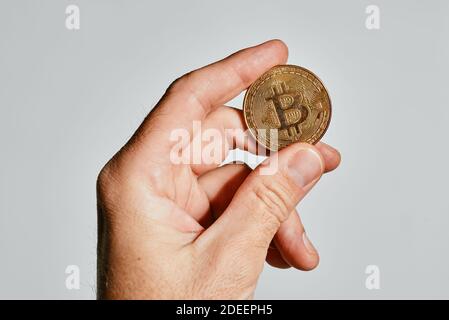 Bitcoin dans la main, monnaie populaire de crypto-monnaie tenue par la personne masculine Banque D'Images