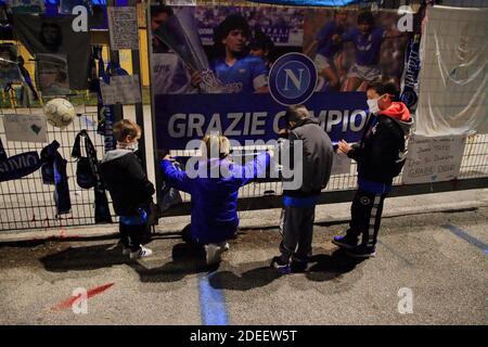 Quelques jeunes enfants mettent un foulard de Naples devant les portes du stade, à la mémoire de Diego Armando Maradona , dans les jours suivant la mort Banque D'Images