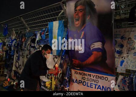 Un jeune fan de Naples allume une bougie, devant les portes du stade, à la mémoire de Diego Armando Maradona , dans les jours suivant la mort Banque D'Images