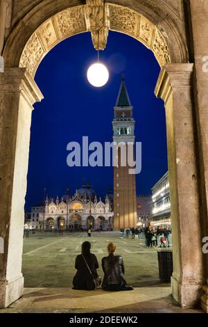 Vue arrière de deux femmes assises devant la Piazza San Marco pour profiter de la belle place et des monuments, Venise, Italie Banque D'Images