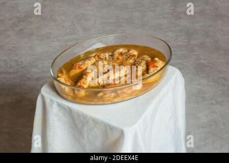 Délicieux filet de poulet cuit avec légumes dans un plat en verre sur une petite table en bois enveloppée dans une nappe de couleur pastel sur un arrière-plan texturé Banque D'Images