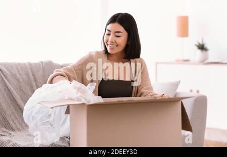 Une femme asiatique souriante a déballé son colis après avoir fait des achats en ligne Banque D'Images