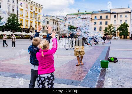 Enfants jouant avec des bulles de savon sur la place du marché principal, Cracovie, comté de Cracovie, petite Pologne Voivodeship, Pologne, Europe Banque D'Images